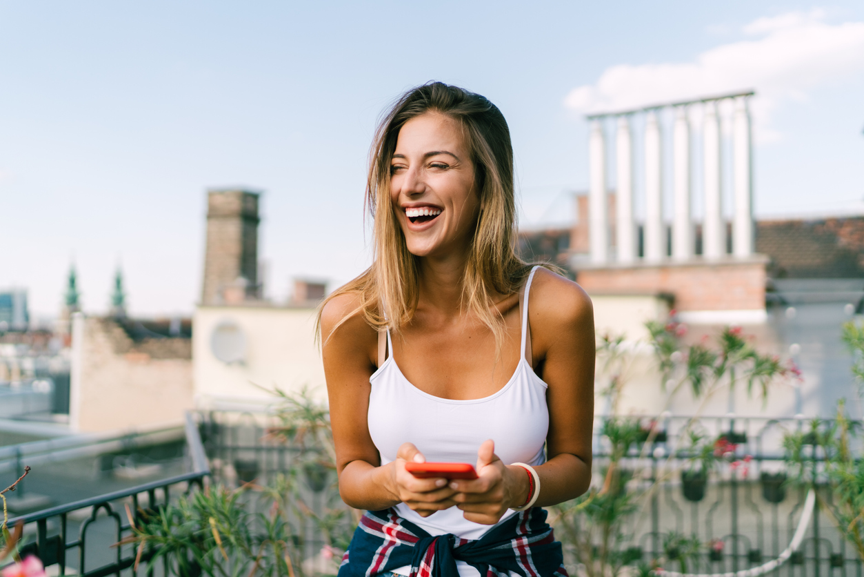 Smiling woman on rooftop terrace having fun in social media